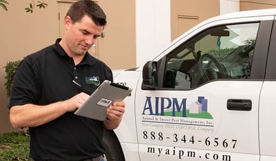 An AIPM professional standing beside an AIPM service vehicle while reading a notepad