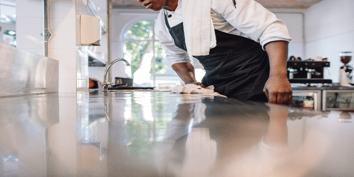 a kitchen staff wiping the table